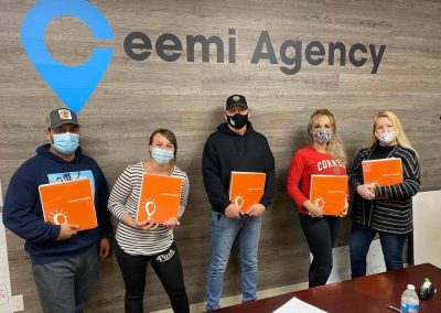 Five people holding orange folders stand in front of a wall with "Ceemi Agency" text. They are wearing masks.