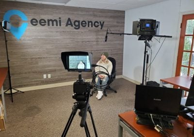 Person sitting in an office, facing a video camera setup, with "Ceemi Agency" logo on the wall.